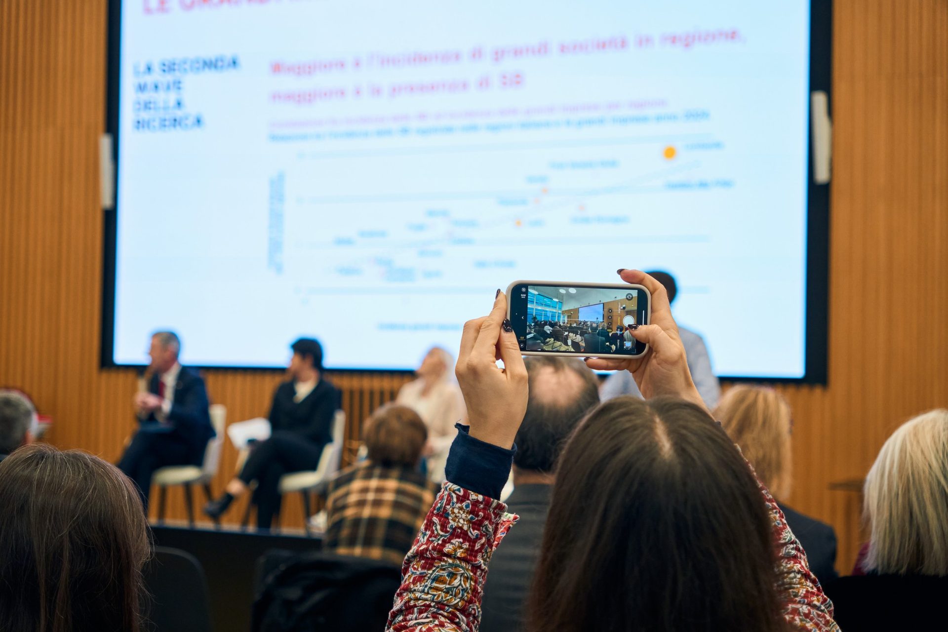 Partecipante che fotografa lo schermo con i dati della Ricerca durante la presentazione